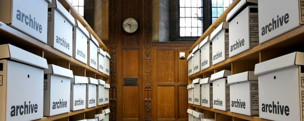 Rows of white archive boxes on wooden shelves.