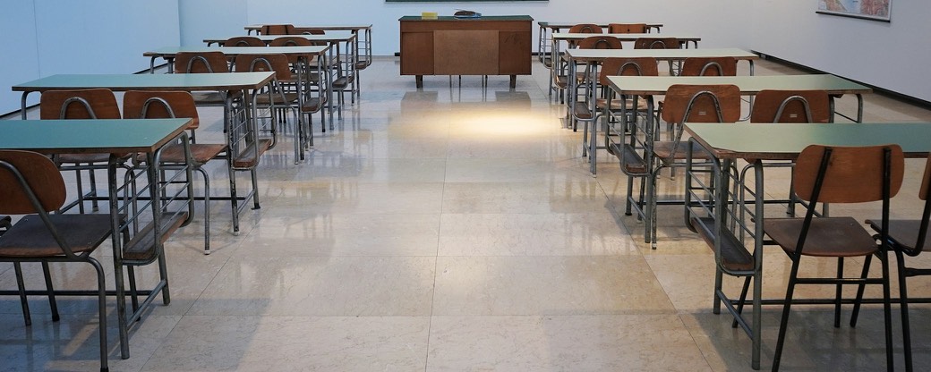 Un'aula vuota con file di banchi rivolti verso una lavagna.